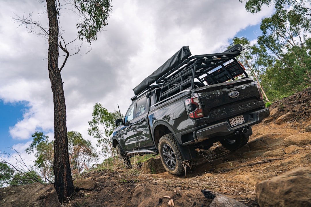 Black pickup truck driving up a rocky, wooded hill.