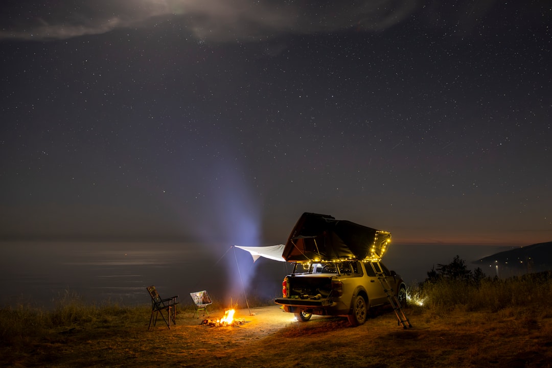 Car with rooftop tent camping under starry night sky